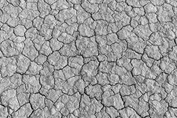 Dry cracked earth texture in black and white,Top view of cracked soil ground during a severe drought. The parched earth shows a high-contrast pattern of deep fissures and dehydrated mud, representing