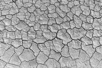 Dry cracked earth texture in black and white,Top view of cracked soil ground during a severe drought. The parched earth shows a high-contrast pattern of deep fissures and dehydrated mud, representing 