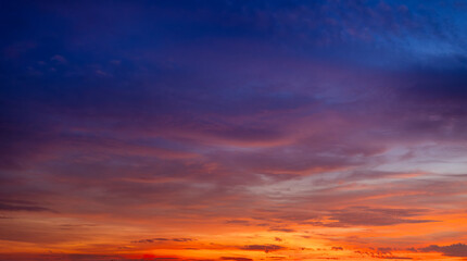 Fototapeta premium Vibrant sunset sky with dramatic orange and purple clouds,A breathtaking sunset sky featuring a beautiful gradient of deep purple, fiery orange, and golden yellow. The wispy cirrus clouds 