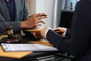 Lawyer giving important documents to client in office meeting.