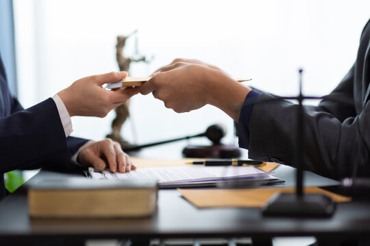 Businessman receiving bribe money in brown envelope from businesswoman at office.
