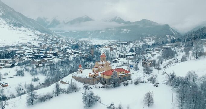 Aerial view of Mestia village and historic church under snow, Georgia. Winter landscape in Caucasus Mountains.