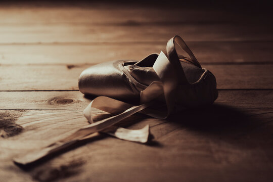pointe shoe or ballet shoe on old wooden floor in brown golden light