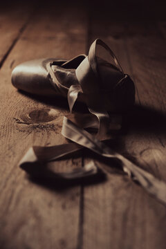 pointe shoes or ballet shoes on old wooden floor in brown golden light