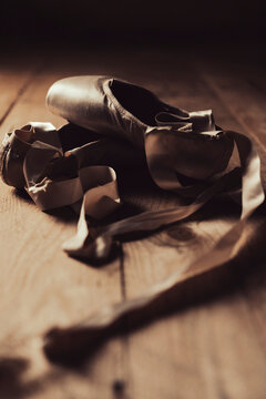 pointe shoes or ballet shoes on old wooden floor in brown golden light