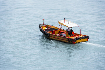 A small wooden boat, manned by one person, sails through the port in Callao, Peru.