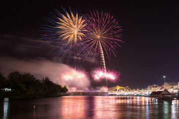 Colorful fireworks lighting up the night sky above the Mae Klong River in Ratchaburi Province, Thailand, creating a festive and celebratory atmosphere, suitable for celebration themes.