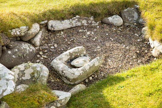 A trough quern and rubbing stone, lying in a midden or rubbish pit, used for grinding corn in the Neolithic and Bronze ages, approx 2500-800 BCE covering the Neolithic, Bronze and Iron ages