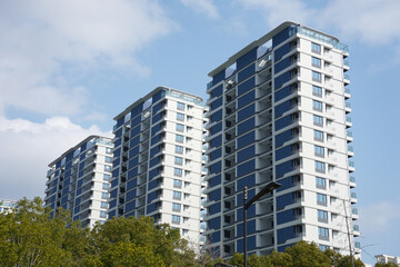 Naklejka premium Three modern high-rise residential buildings with blue and white facades captured from a low-angle perspective