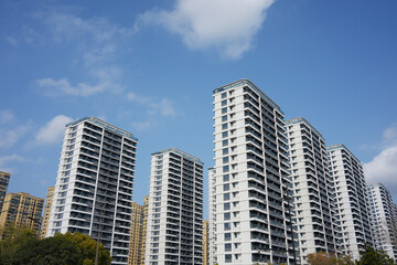 Fototapeta premium Modern high-rise residential buildings under a clear blue sky with white clouds
