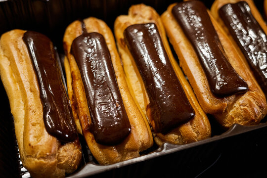Chocolate eclairs are arranged on a tray ready to be served at a dessert shop in the afternoon