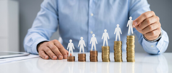 Businessman arranging paper figures on stacks of coins representing salary growth concept