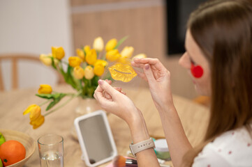 Young caucasian woman sitting ate the table and using eye and lip patches