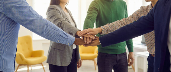 Diverse team members stacking hands together in unity gesture for collaboration and support