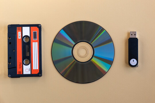 Cassette tape, compact disc and USB flash drive on neutral background. Technology progress and media evolution concept.