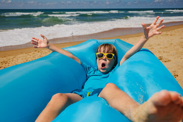 Kid have fun at summer beach vacation on inflatable lounger