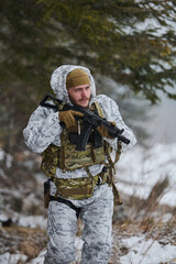 Fototapeta premium Soldier in Winter Camouflage Carrying Rifle Through Snowy Forest During Cold Weather Patrol