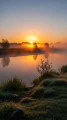 Obraz premium Sunrise over a misty lake with tranquil reflections and calm dawn light.