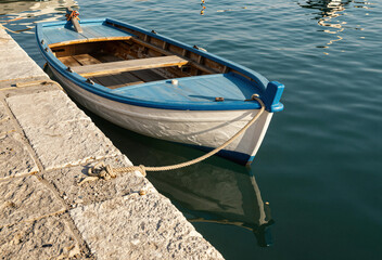Weathered dock corner with blue-white boat and turquoise water