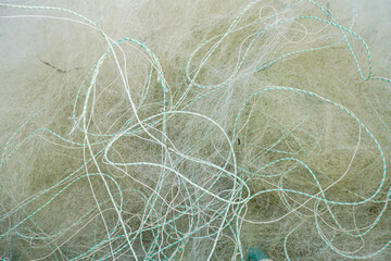 Fototapeta premium tangled white and green fishing net with frayed threads