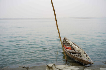 weathered wooden boat tied with bamboo pole on calm water