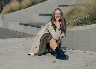 Young caucasian female in stylish outfit sitting outdoors on a sunny day