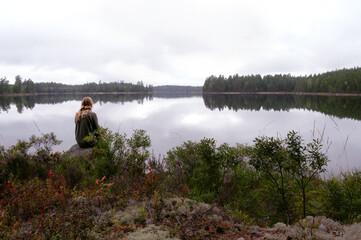 Person sitting by calm forest lake in peaceful nature setting
