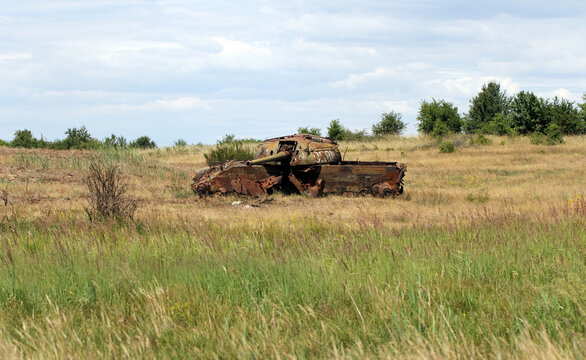 A destroyed, rusting tank in a meadow. A battlefield, war, a combat training ground.