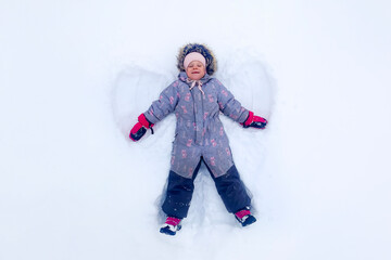 A joyful girl portrays a snow angel