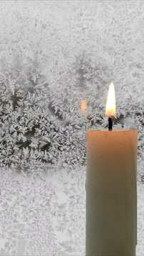 A candle burns against the background of a frozen window №5