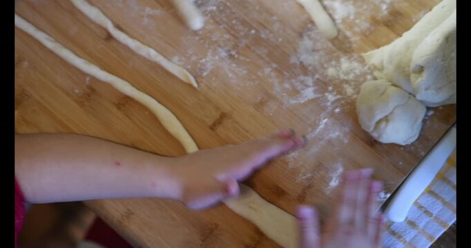 Woman making homemade pasta potato gnocchi. Dropping the dough pieces onto the floured wooden table.