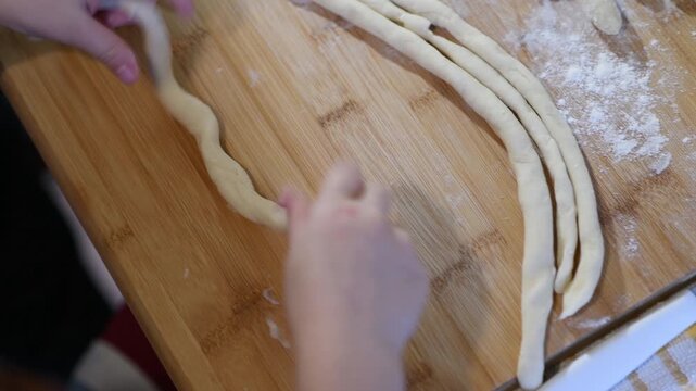Woman making homemade pasta potato gnocchi. Dropping the dough pieces onto the floured wooden table.
