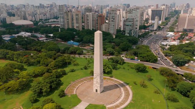 Aerial view crane up and orbiting around Obelisco de Sao Paulo at Ibirapuera Park in Sao Paulo, Brazil. Drone shot revealing monument from multiple angles