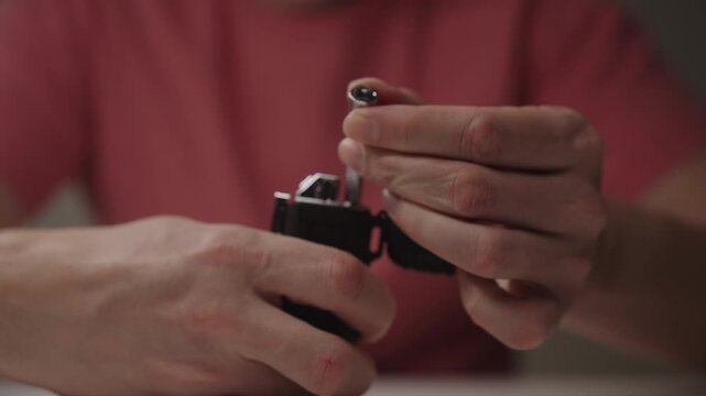 Close-up view of male hands holding black electronic plasma lighter, opening cap, extending flexible neck and pressing button to activate purple electric arc. Shooting in slow motion.