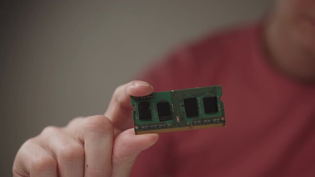 Close-up hands of unrecognizable technician holding ram module, performing component inspection, diagnosing computer hardware, upgrading memory and maintaining electronic device performance.
