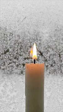A candle burns against the background of a frozen window №7