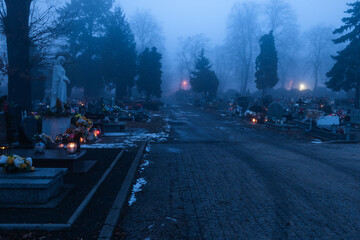 Cmentarz komunalny w mieście Żagań w Polsce. Cmentarna alejka w zimowy, mglisty wieczór.  © boguslavus