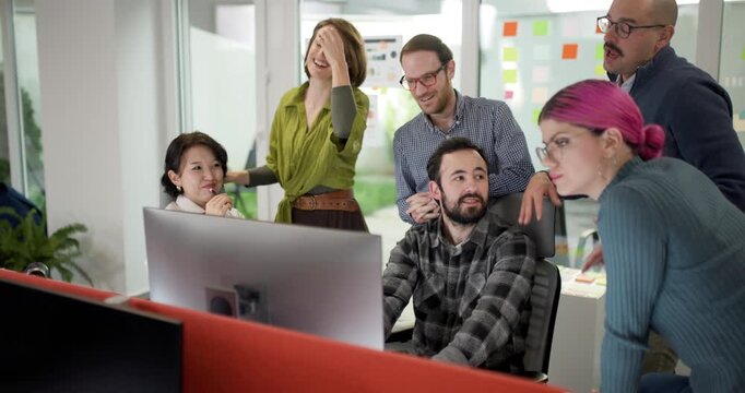 Team discusses project ideas in office with business professionals gathered around a computer during work hours