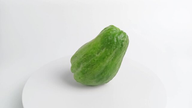 Fresh green chayote or Sechium edule rotating on white podium, healthy vegetable food ingredient concept.
