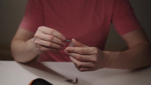 Closeup of man storing soldering iron tips in small plastic container, organizing tools and accessories after completing intricate electronics repair and hobby work, maintaining workbench efficiency.