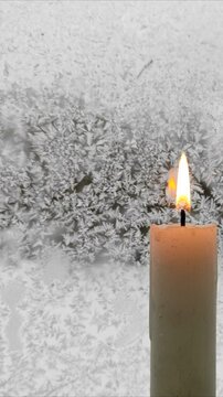 A candle burns against the background of a frozen window №8