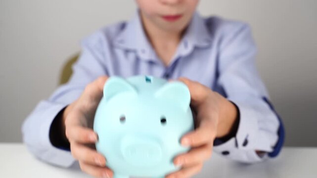 Boy collecting coins or money in a piggy bank
