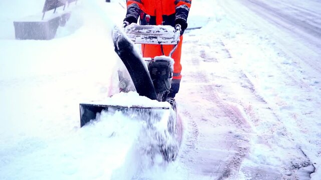 A man with a snow blower removes snow