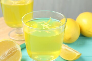 Yummy yellow jelly in dessert bowls and lemons on light blue wooden table, closeup