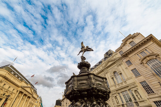 Piccadilly Circus Eros Statue And Historic Fountain In London Under Blue Cloudy Sky