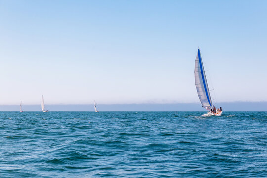 Sailboat Racing on the Open Sea With Blue Sails and Crew on a Sunny Day