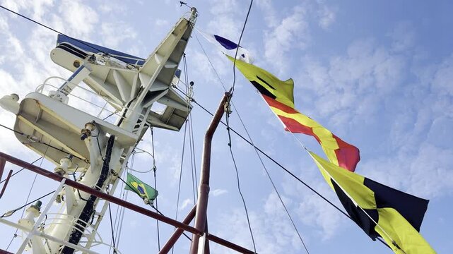 Dressed overall ship rigging. Bright bunting and nautical signal flags blowing in the wind on a commercial freighter to mark a special occasion and crew celebration against blue sky. 