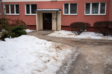 posypany piachem chodnik na osiedlu, topniejący śnieg, blok w tle © Katarzyna
