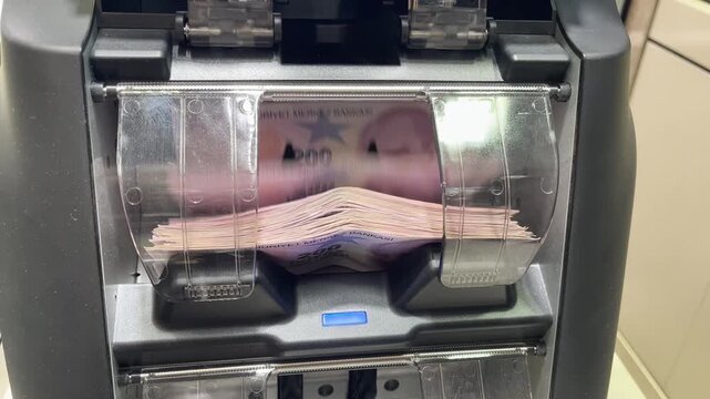 Close-up detail image of 200 Turkish Lira banknotes being rapidly counted in an automatic cash counting machine; representing finance, banking, and cash flow.