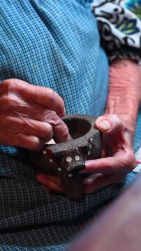 Ederly hands using a traditional Mexican molcajete, detail of aged skin with sunspots and wrinkles on elderly hands